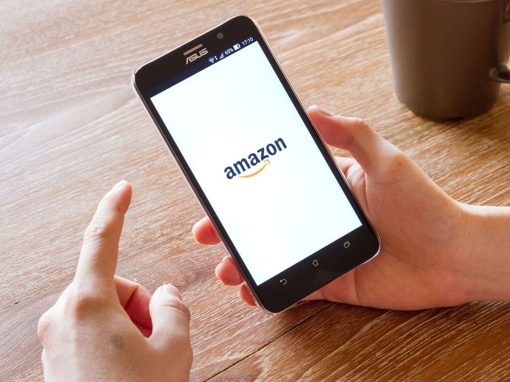 Hand holding a smartphone with the Amazon logo