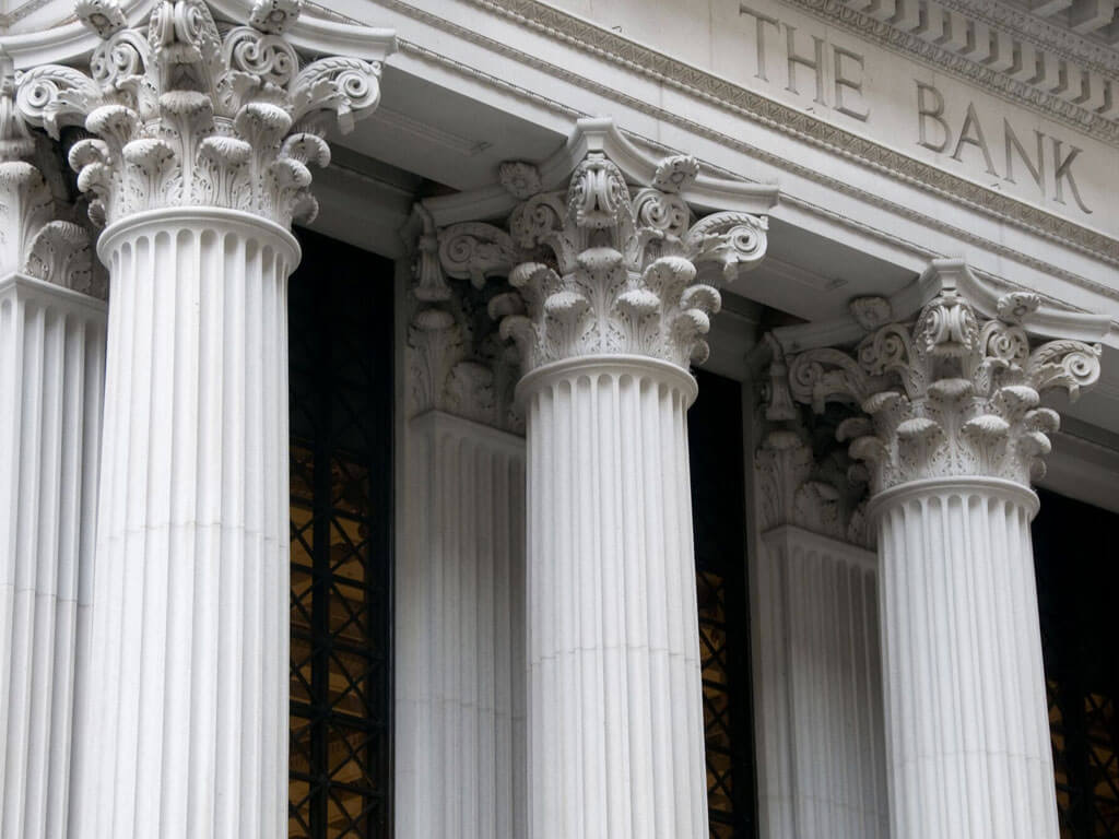 Closeup of an ancient Greek style building with the words The Bank engraved