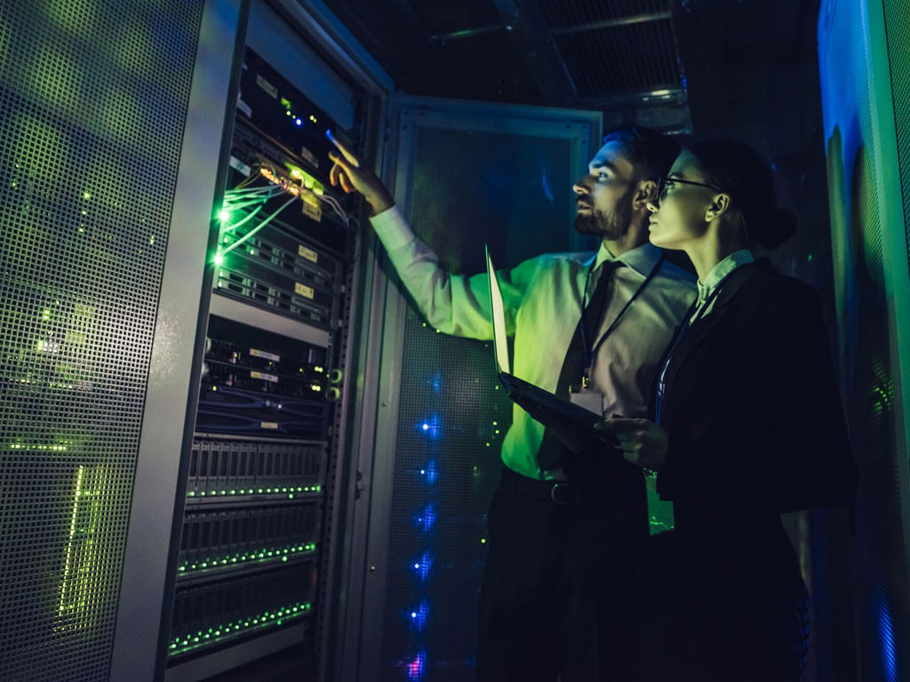 Two people looking at the back of servers