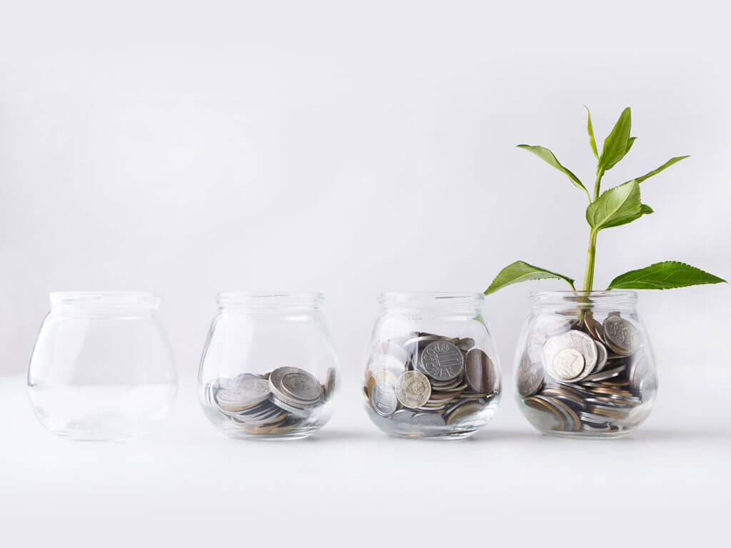 4 glass jars with growing number of coins