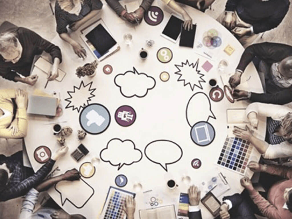 Group of people sitting on a round table having a meeting