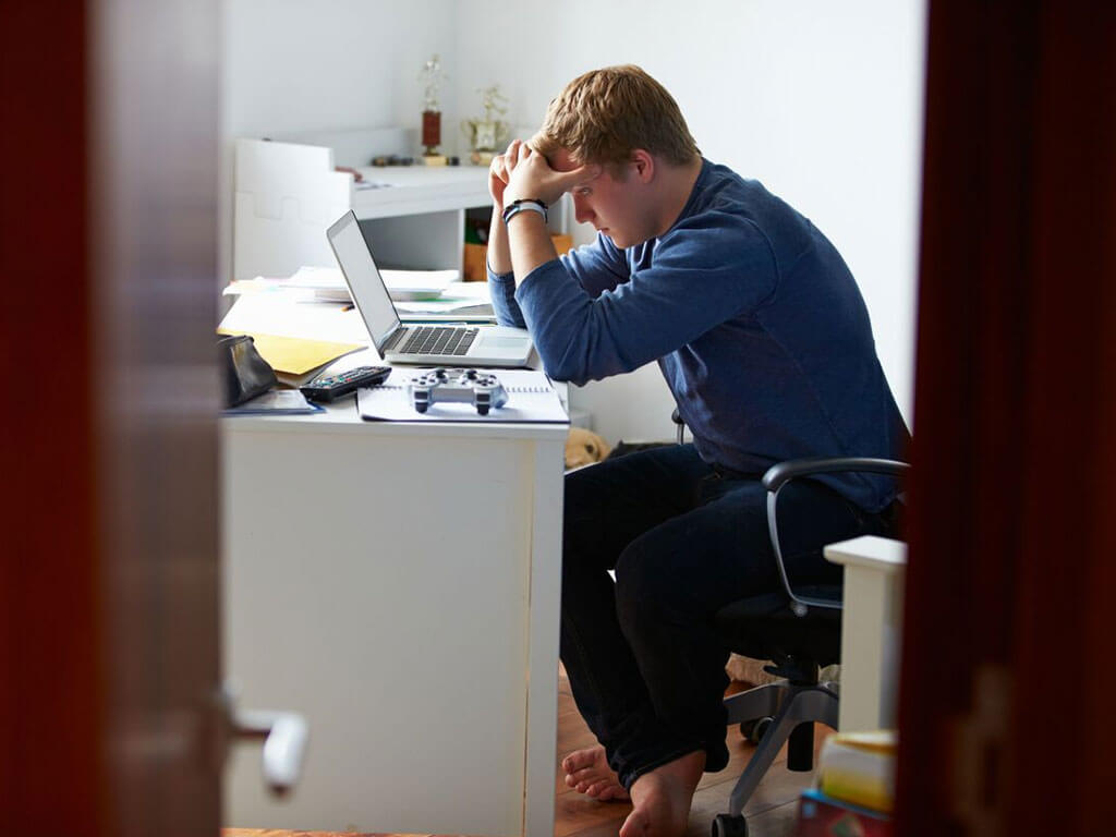 Young man looking worried over a laptop