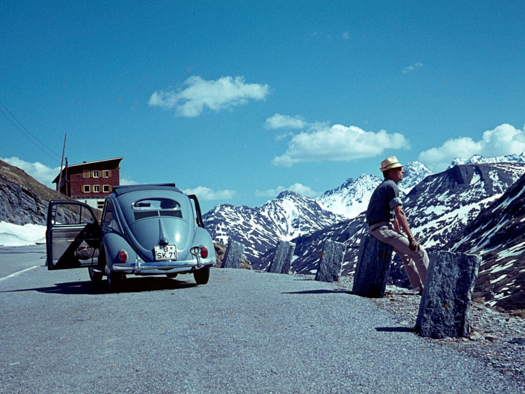 Old beetle car on the left - a man sitting on the right looking the other way