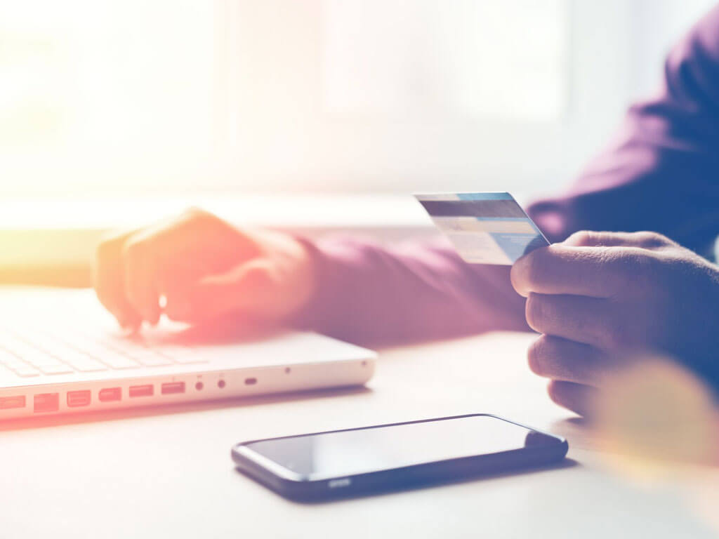 Person holding a credit card and using a laptop