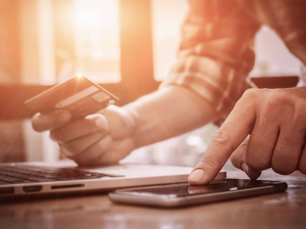 Someone holding a credit card while using a smartphone