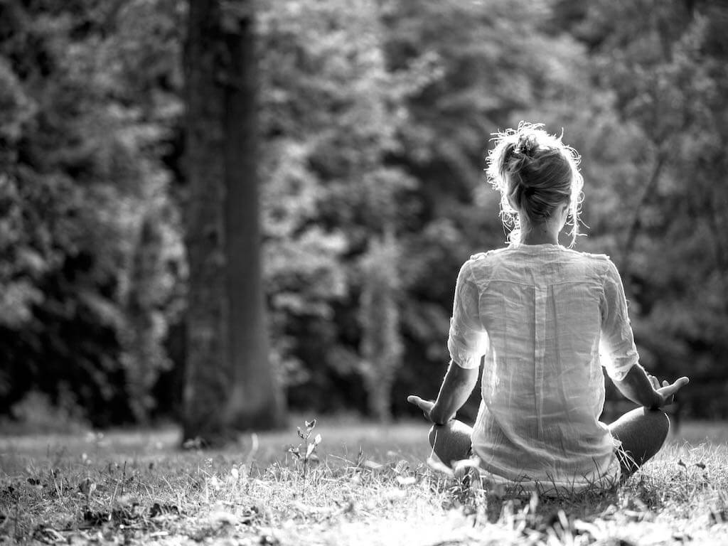 Woman meditating, sitting on the grass