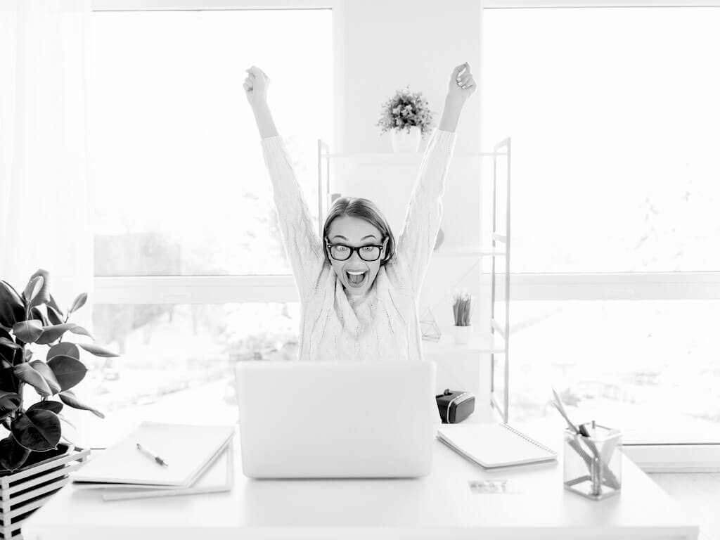 Young woman celebrating at a laptop