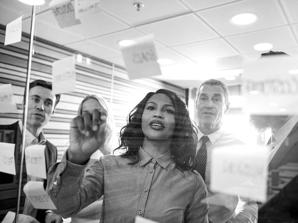 People looking at notes stuck on a glass wall