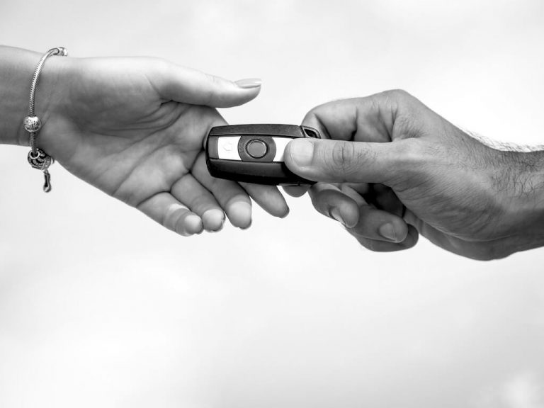 Hand giving car key fob to another hand