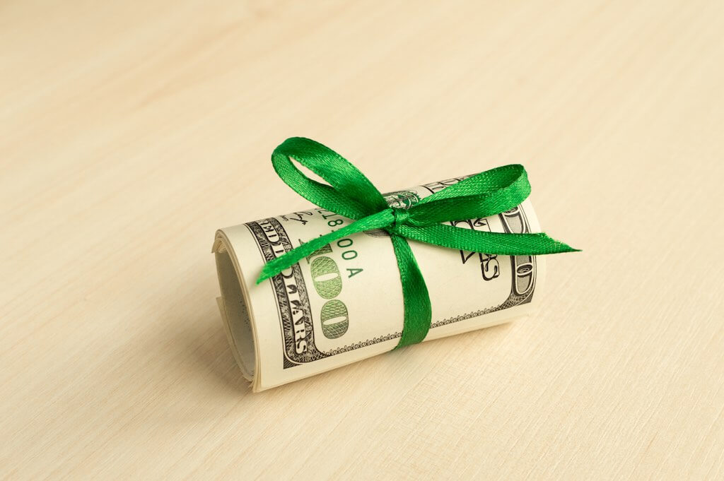 Money wrapped up with a green ribbon